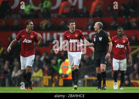 Schiedsrichter Mike Dean (rechts 2) wird von den Manchester-United-Spielern Rio Ferdinand (links) und Michael Carrick (Mitte) umzingelt, nachdem er das von Jonny Evans von Manchester United erzielte Eigentor vergibt Stockfoto