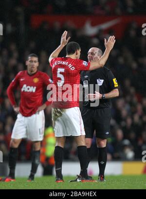 Rio Ferdinand von Manchester United (links) beklagt Schiedsrichter Mike Dean (rechts) Stockfoto