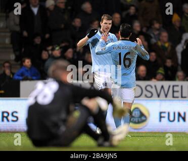 Der Manchester-City-Edin Dzeko (hinten links) feiert mit seinem Teamkollegen Sergio Aguero (rechts), nachdem sein Schuss von Norwich City Torhüter Mark Bunn für ein Eigentor ins Netz gestellt wurde und der vierte seines Teams Stockfoto