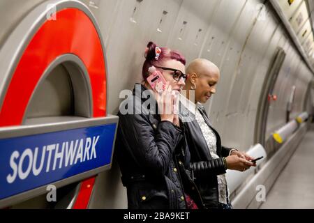 Ein Mann telefoniert auf dem Bahnsteig an der U-Bahn-Station Southwark, die Teil des U-Bahn-Systems London ist Stockfoto