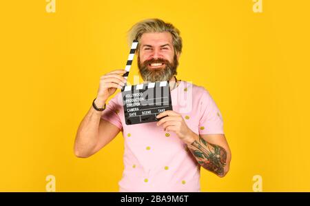 Bärtiger Mann hält Filmklapper. Filmkonzept. Platz für das Kopieren auf dem Clapperboard. Film ansehen. Filmregisseur. Schauspielercasting. Aufnahmeszene. Lieblingsserie. Aktion. Kinoproduktion. Kreativer Produzent. Stockfoto