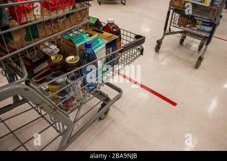 23. März 2020 - Montreal, QC, Kanada: Produktlinien und Lebensmittelwagen mit Aufkleber auf dem Boden, Supermarkt, Coronavirus (COVID-19) Pandemie-Krise Stockfoto