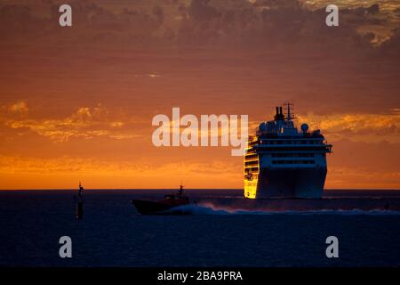 Eine Kreuzfahrt vor dem Ufer verankert soaks in einem epischen blutroten Sonnenuntergang. Westaustralien Stockfoto