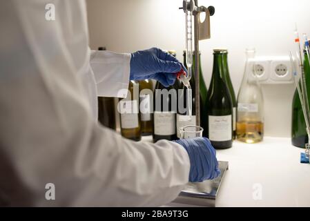 Nahaufnahme des Laboranten durch Auflegen einer Probe auf den Becher. Stockfoto