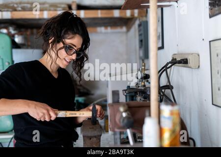 Frauen arbeiten mit Hammer und Amboss im Künstleratelier Stockfoto