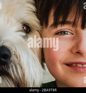 Nahaufnahme der Hälfte der Gesichter von Junge und Hund mit Köpfen zusammen. Stockfoto