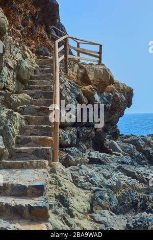 Schöner Blick auf das blaue Meer von der Treppe mit Holzgeländer und Stein der Hintergrund Horizont an einem klaren Tag in Ajuy, Fuerteventura, Kanarische Stockfoto