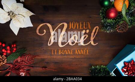 "Joyeux Noel et Bonne Annee" t.i. Frohe Weihnachten und frohes neues Jahr in französischer Sprache auf Holzhintergrund mit dekorativen vertikalen Ansichten für Smart Stockfoto