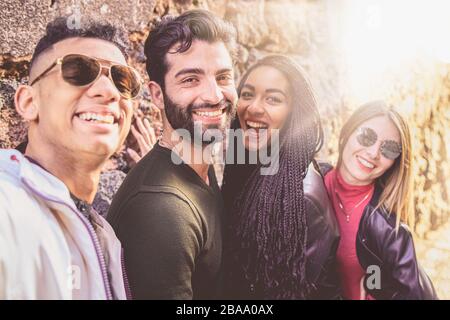 Portrait einer Gruppe junger multiracial Leute, die Spaß haben, ein selfie mit ihren Smartphones zu nehmen. Tausendjährige Menschen im Freien, die uns Selbstporträts machen Stockfoto