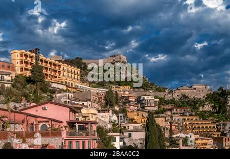 Schöner Blick auf das bewohnte Zentrum der Bergstadt Taormina, Messina, Sizilien, Italien, gegen einen dramatischen Himmel Stockfoto