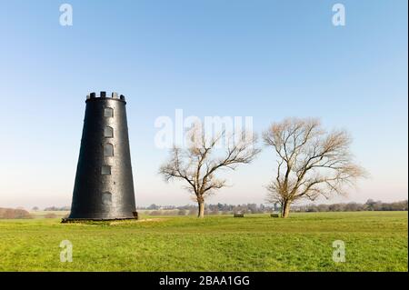 Black Mill, ein lokales Wahrzeichen, das von grünen Bäumen unter blauem Himmel im Westwood im frühen Frühjahr in der Nähe von Beverley, Yorkshire, Großbritannien, flankiert wird. Stockfoto