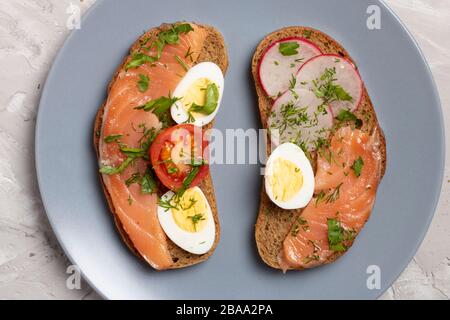 Frühstück knuspriges Sandwich mit Wachtelei, Tomaten, Ziegenkäse, grünen Erbsen, Rettich, Gurke. Draufsicht Stockfoto