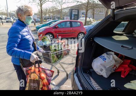 Southampton, England, Großbritannien. 2020. Eine ältere Frau, die während der Coronavirus-Epidemie eine Gesichtsmaske und Gummihandschuhe trägt und Einkaufen in ein Auto lädt Stockfoto