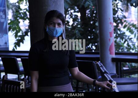 Eine kamboische Kellnerin, die während der Coronavirus-Pandemie eine Gesichtsmaske in einem Restaurant/einer Bar am Flussufer trägt. Phnom Penh, Kambodscha. © Kraig Lieb Stockfoto