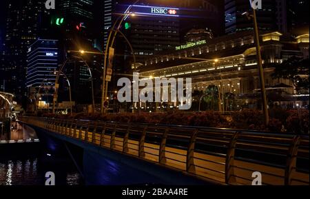 Das Fullerton Hotel, Singapur, beleuchtete nachts mit dem Finanzviertel hinter und leichtem Aufflackern Stockfoto