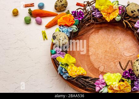 Festlicher Ostertisch. Handgearbeiteter Oster-Korbkranz mit Wachteleiern und handgefertigten Blumen. Birkenzweige, Polka Punkt satiniertes Band. Weiße PU Stockfoto