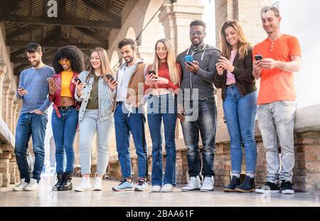 Eine Gruppe von Freunden in einer Reihe verwendet Smartphones. Jugend nutzt soziale Netzwerke und neues Technologiekonzept. Hochformat in voller Länge. Stockfoto