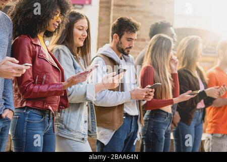 Gruppe von multirassischen Freunden, die in einem rohen, von sozialen Netzwerken abhängigen Netzwerk entsorgt wurden. Studenten nutzen Smartphone- und Internetsuchkonzept. Stockfoto