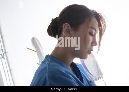 Erschöpfter junger weiblicher Arzt reibt die Augen Stockfoto