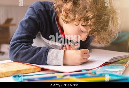 Cute kid Schreiben auf ein Heft in seinem Haus. Volksschule lifestyle Menschen Konzept Stockfoto