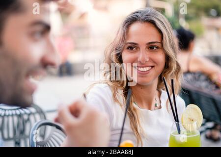 Ein paar Freunde trinken Cocktails an einem Restauranttisch. Eine Gruppe von Leuten, die Spaß beim Chatten haben und sich auf einem Couchlader entspannen. Stockfoto