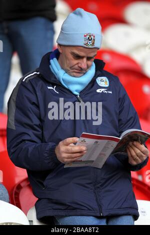 Ein Fan von Coventry City liest das Spieltagsprogramm auf den Tribünen Stockfoto