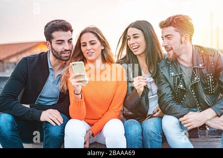 Eine Gruppe junger tausendjähriger Leute, die Spaß am Smartphone haben. Junge Freunde, die ein lustiges Video über eine Social-Media-Anwendung ansehen und gemeinsam lachen Stockfoto