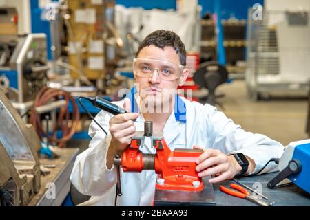 Arbeiter in der Metallverarbeitungsanlage schleift Metallteile auf Schraubstock Stockfoto