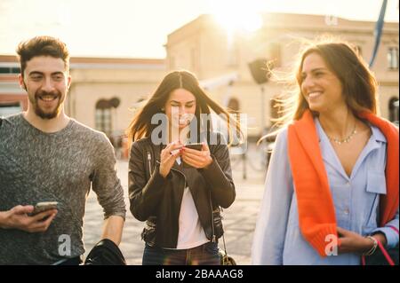 Freundschaft der Generation der Millennials, die Spaß beim gehen und verwenden von Smartphones hat. Lifestyle-Konzept für die mittlere Saison. Stockfoto
