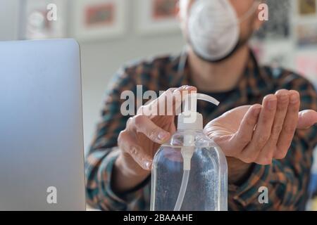 Coronavirus. Mann, der von zu Hause aus mit Schutzmaske arbeitet. Quarantäne für Coronavirus mit Schutzmaske. Arbeiten von zu Hause aus. Ihre Hände reinigen Stockfoto