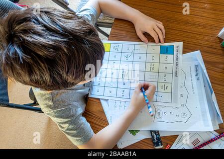 Ein kleiner Junge, der im Rahmen eines Mathe-Themenspiels an Mathematikrätseln arbeitet. Dies ist Teil des Lernens zu Hause als Folge der Coronavirus-Pandemie.