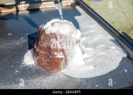 Ein Vulkanausbruch wird mit Bicarbonat aus Soda und Essig simuliert. Es wird Kohlendioxid freigesetzt, das in einem Vulkan die Larve schäumt und ähnelt. Stockfoto