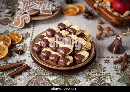 Weihnachtskekse mit Marmelade gefüllt und in Schokolade auf einen Tisch getaucht Stockfoto