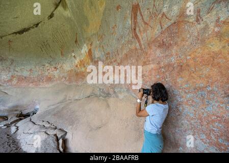 Ein Tourist fotografiert die Kunst des San Rock in der Inanke Cave, Matobo National Park, Simbabwe. Stockfoto