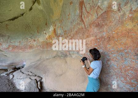 Ein Tourist fotografiert die Kunst des San Rock in der Inanke Cave, Matobo National Park, Simbabwe. Stockfoto