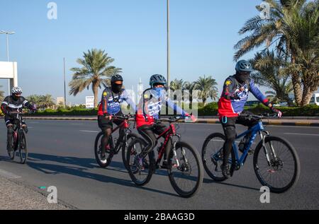 Kuwait City, Kuwait - Gruppe von Radfahrern, die auf einer leeren Straße auf der Arabischen Golfstraße mit Gesichtsmasken fahren, Nov2019 Stockfoto