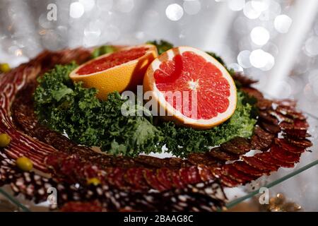 Verschiedene Würstchen mit Grapefruit und Salat werden auf Glasschale serviert, flacher Lay. Selektiver Fokus. Firmengeburtstag oder Hochzeit Stockfoto
