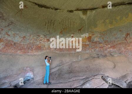 Ein Tourist fotografiert die Kunst des San Rock in der Inanke Cave, Matobo National Park, Simbabwe. Stockfoto