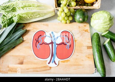 Menschliche Nieren, die mit frischen grünen Lebensmitteln auf dem Schneidebrett ziehen, Ansicht von oben. Gesundheitskonzept für die Nieren von Lebensmitteln Stockfoto
