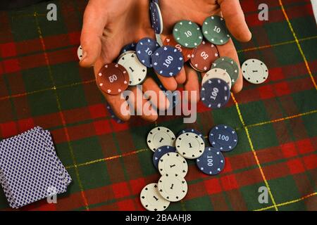 Man hält Karten und Poker-Chips in seinen Händen Stockfoto