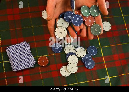 Man hält Karten und Poker-Chips in seinen Händen Stockfoto