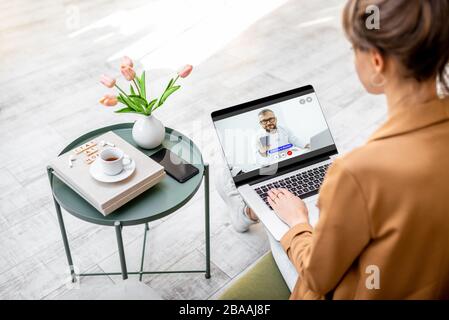 Geschäftsfrau, die online mit einem Arzt beraten hat, während sie zu Hause sitzt. Arbeit von zu Hause und von der Medizin während einer Quarantäne Stockfoto
