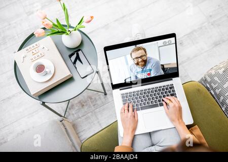 Geschäftsfrau mit einem Videoanruf mit Kollegen, die online von zu Hause aus in gemütlicher Atmosphäre arbeitet Stockfoto