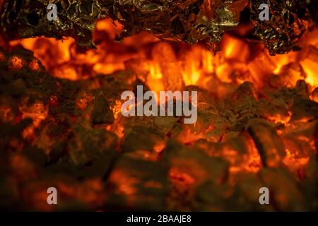Heiße Kohlen im Grill während der Zubereitung von Speisen in Folie Stockfoto