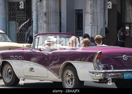 Touristenfamilie, die in einem klassischen violetten amerikanischen Auto in Centro Havanna umhergefahren wird Stockfoto