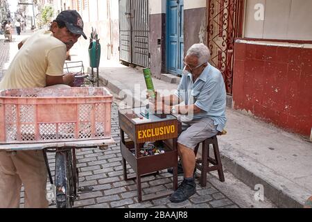 Der alte Cubam-Straßenhändler, der Zigarren- und Zigarettenanzünder auf der Straße in Centro Havanna nachfüllte Stockfoto