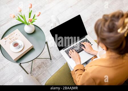 Frau, die zu Hause am Computer arbeitet, Laptop mit schwarzem Bildschirm zum Kopieren von Paste, Ansicht von oben. Konzept eines Heimwerks in gemütlicher Atmosphäre Stockfoto