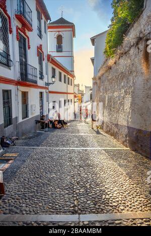 Blick auf die schmale Straße mit typischen gepflasterten Straßenbelägen im albaicinisch-arabischen Viertel. Granada, Andalusien, Spanien Stockfoto