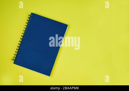 Nahaufnahme eines vollständig blau gefärbten normalen Tagebuchs vor gelbem Papierhintergrund Stockfoto
