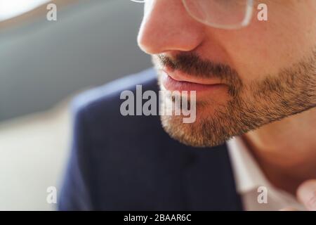 Moderner kaukasischer Mann in stilvollen Brillen, die drinnen sitzen Stockfoto